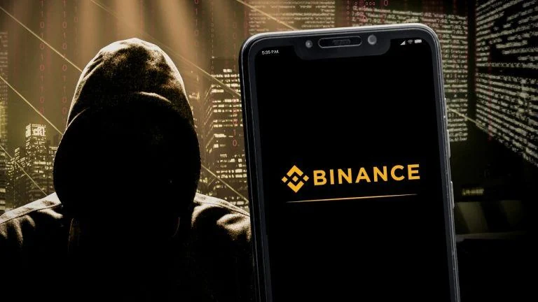 Binance logo on the smartphone screen and the concept of hacker at the blurred background